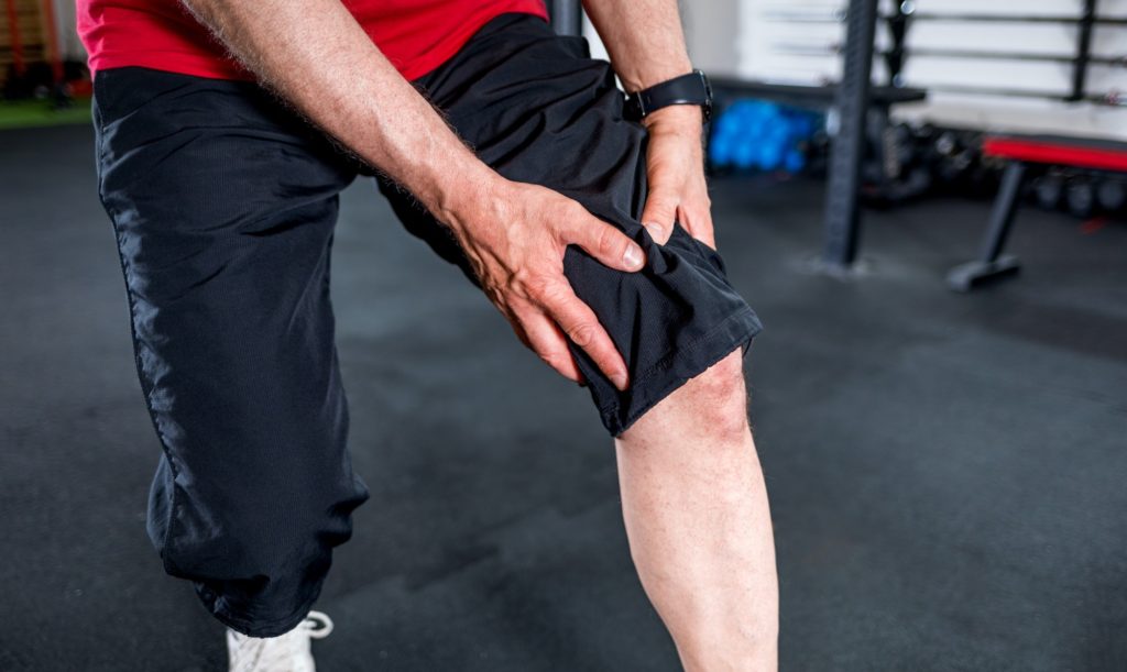 Senior man at the gym suffering from pain in knee